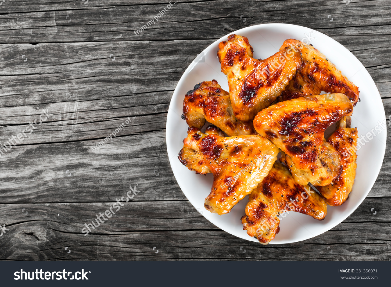 tasty grilled chicken wings on a white dish, top view #381356071