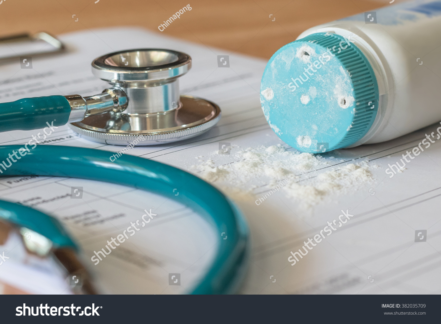 Baby powder product with talc mineral spilling over diagnosis record paper on doctor's pad with stethoscope in teal color background #382035709