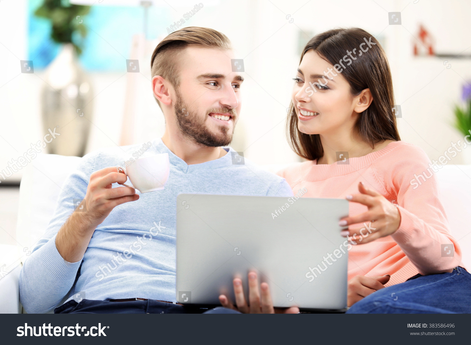 Happy couple working on laptop in a room #383586496