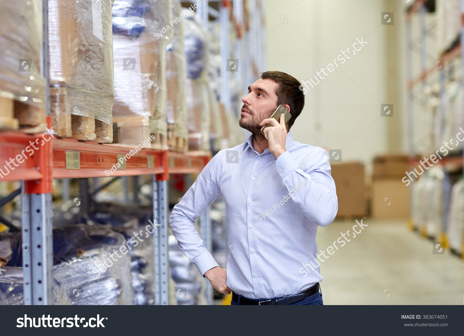 wholesale, logistic, business, export and people concept - serious businessman calling on smartphone at warehouse #383674051