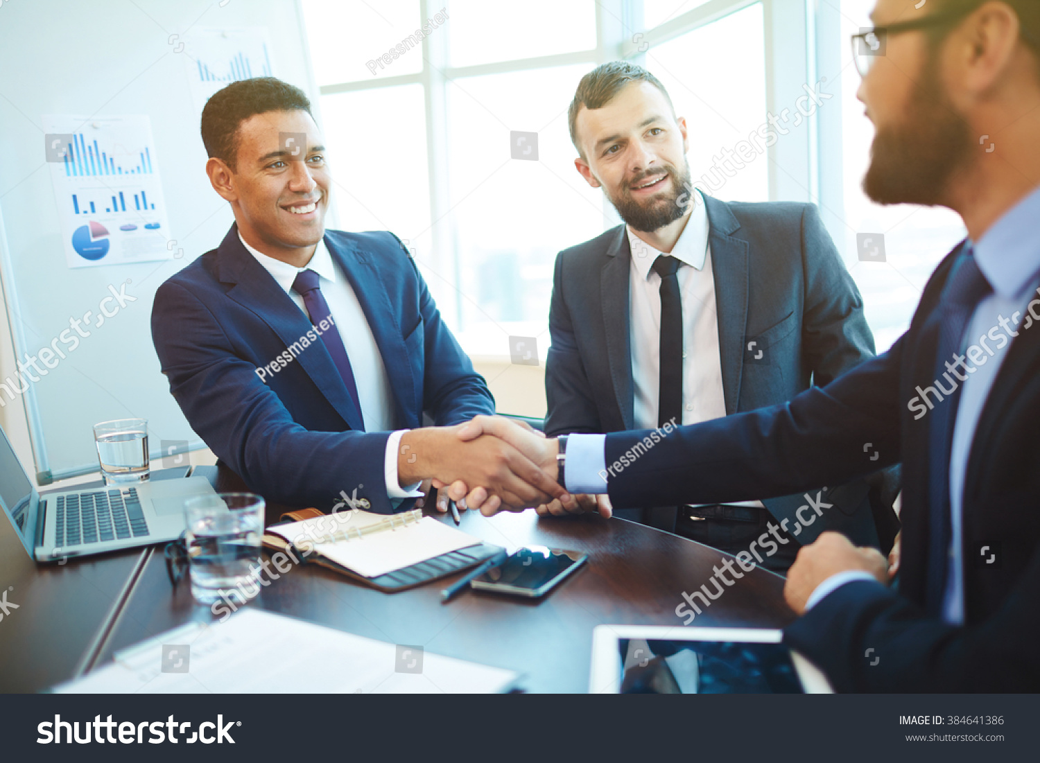 Businessmen shaking hands during a meeting #384641386