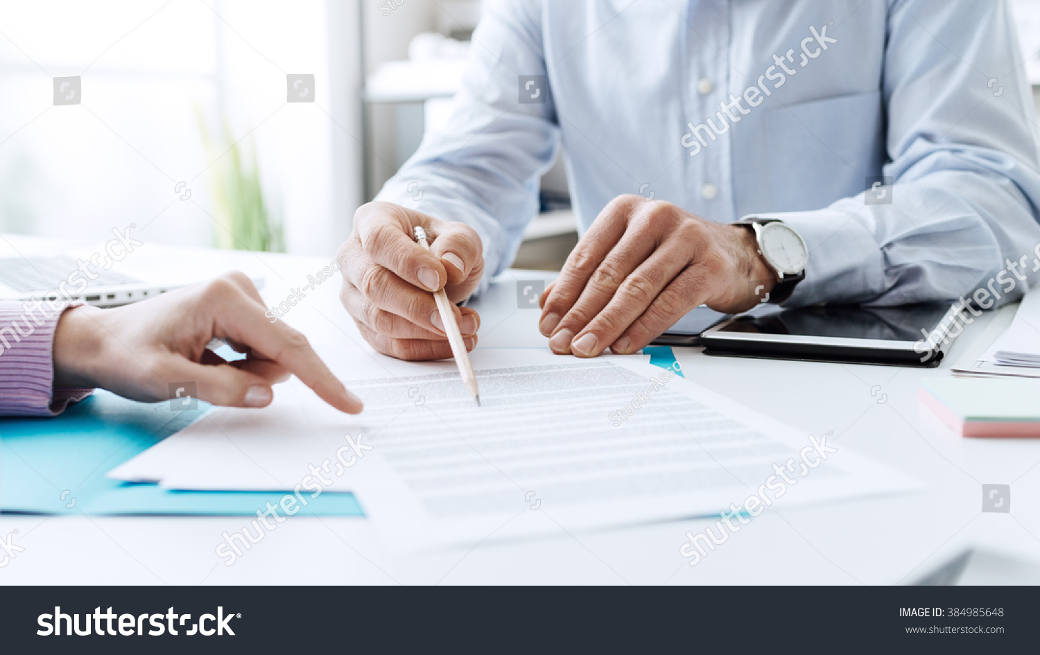 Business people negotiating a contract, they are pointing on a document and discussing together #384985648