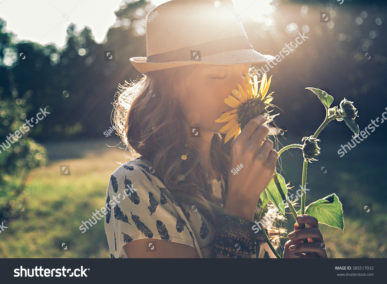 Girl smells sunflower in nature #385517032