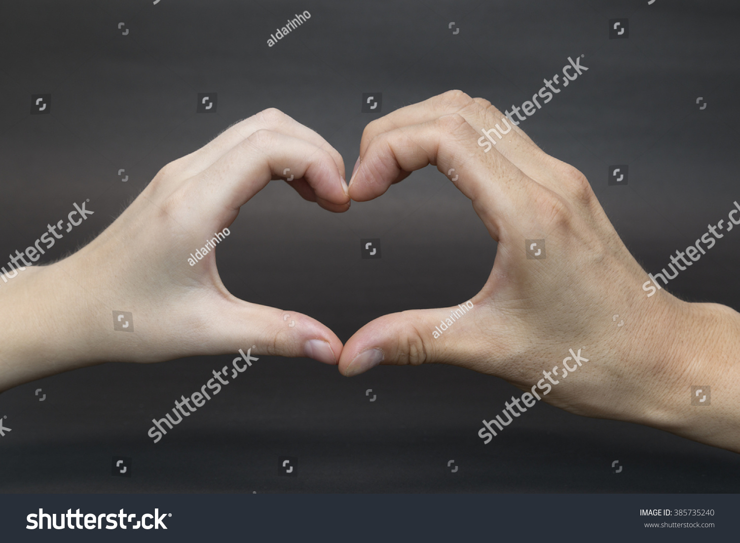 Hands shaped in heart on black background #385735240