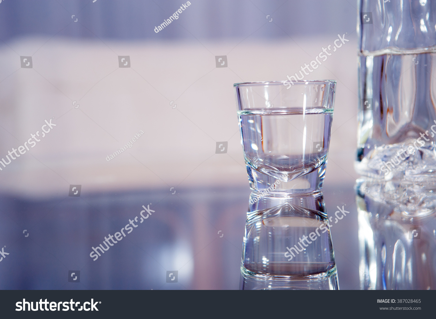 A vodka glass with a bottle standing on the glass table / vodka glass #387028465