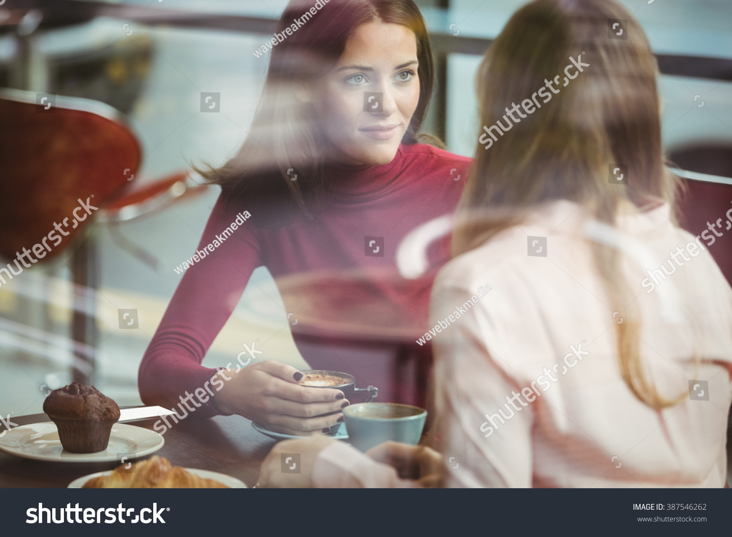 Pretty friends chatting over coffee in cafe #387546262