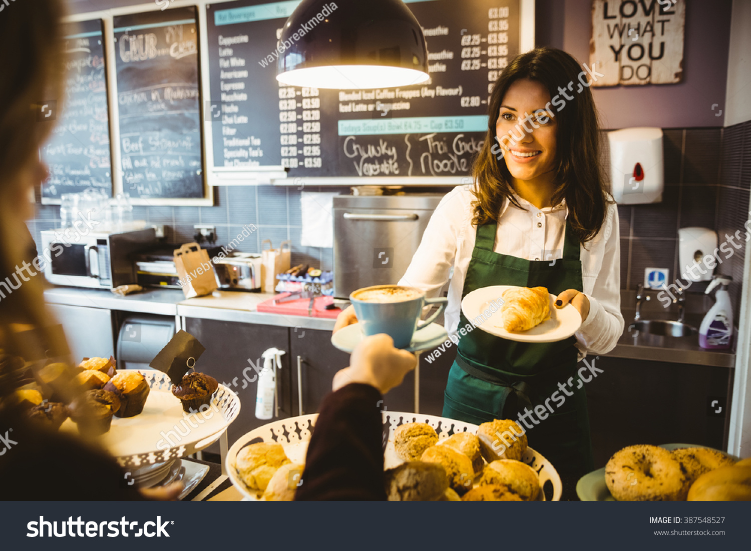 Waitress serving a cup of coffee in cafe #387548527
