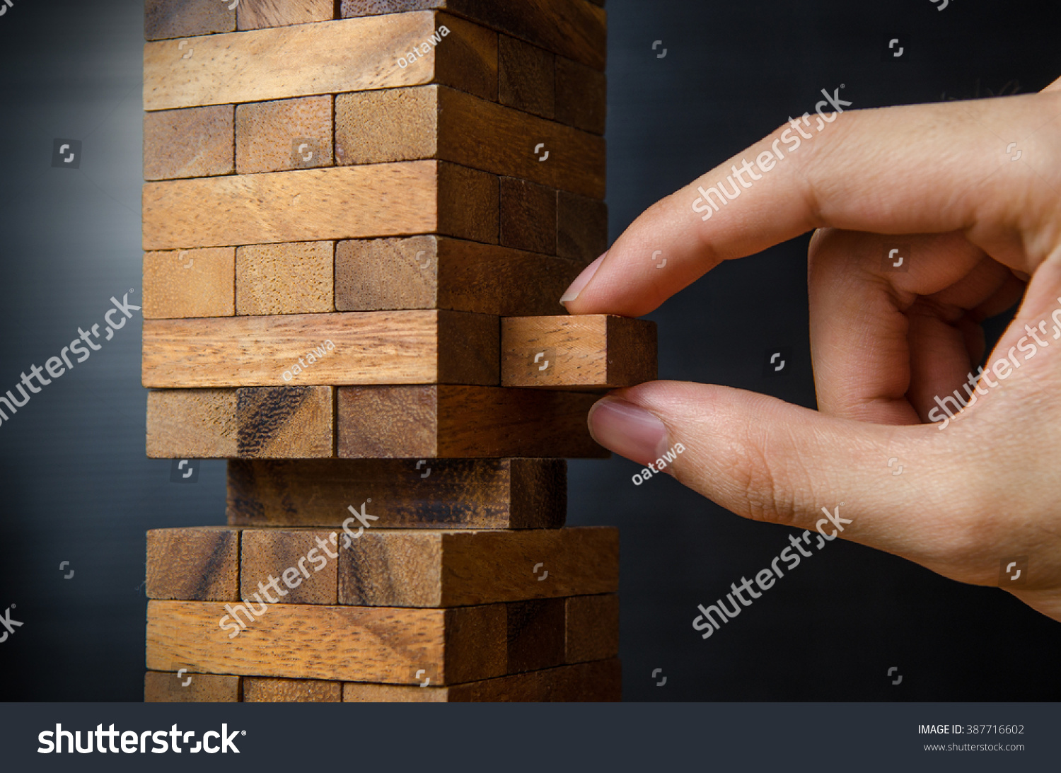 Closeup hand man take one block on The tower from wooden blocks, dark tone. #387716602