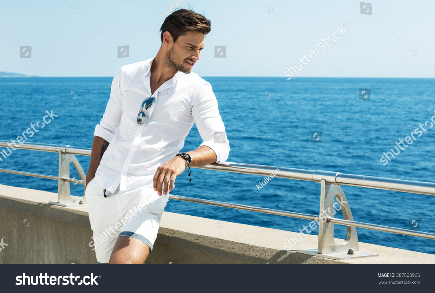 Handsome man wearing white clothes posing in sea scenery #387823966