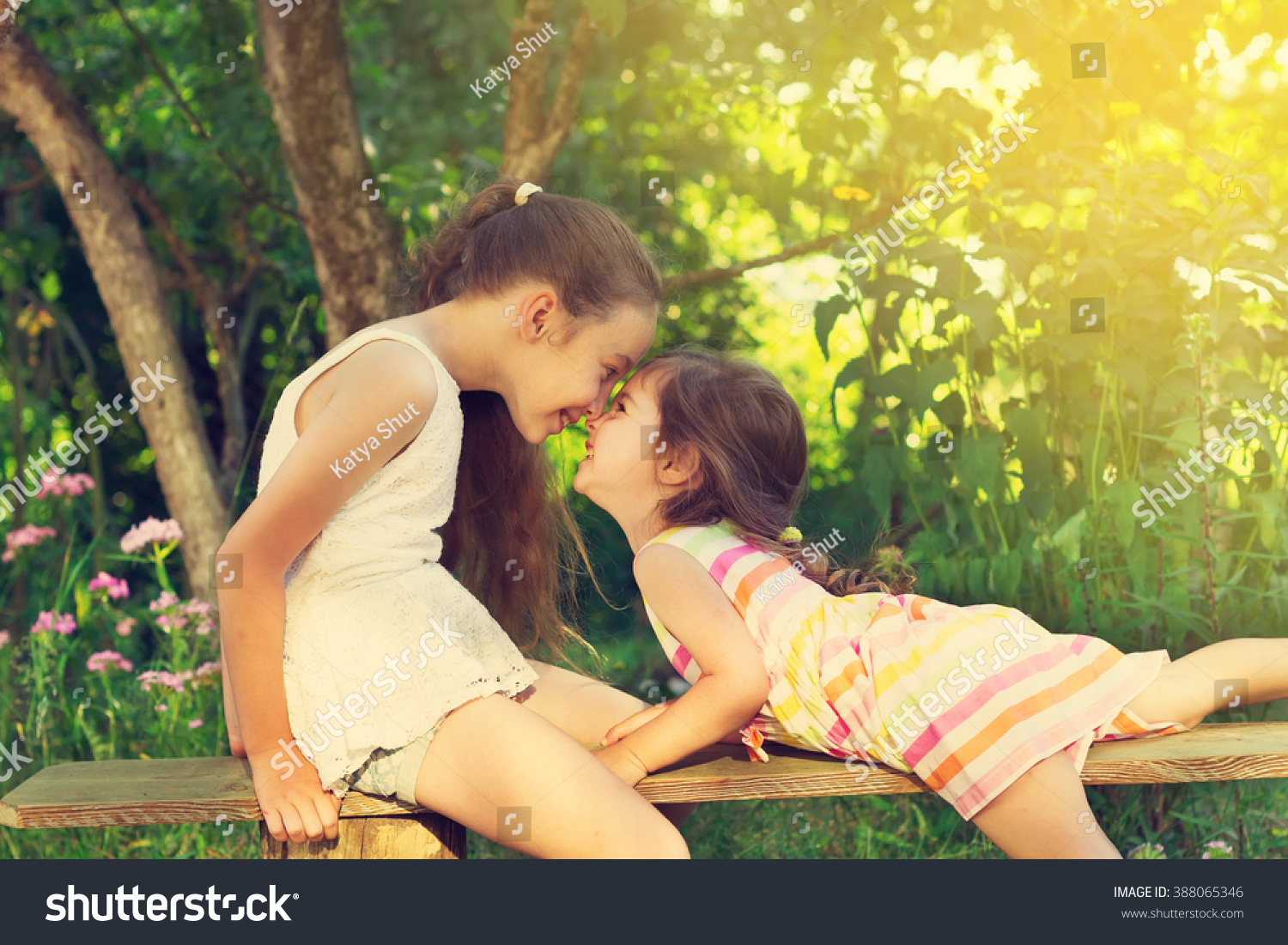 Toned portrait of two cute little girls smiling and playing at the garden #388065346