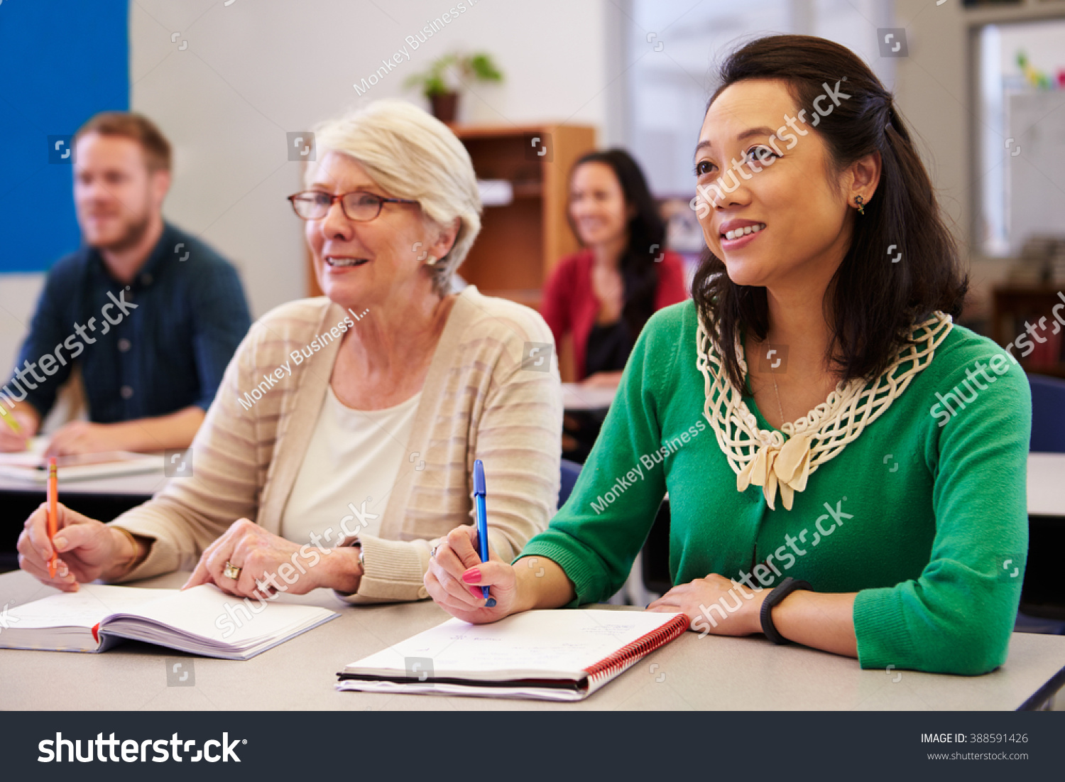 Two women sharing a desk at an adult education class look up #388591426
