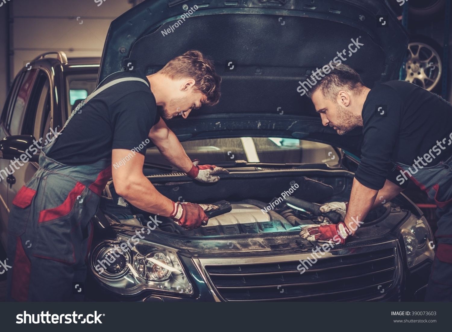 Professional car mechanics checking under hood in auto repair service. #390073603