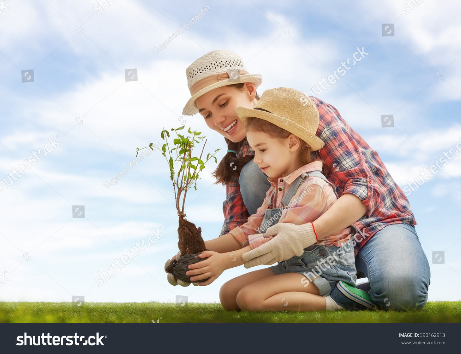 Mom and her child girl plant sapling tree. Spring concept, nature and care. #390162913