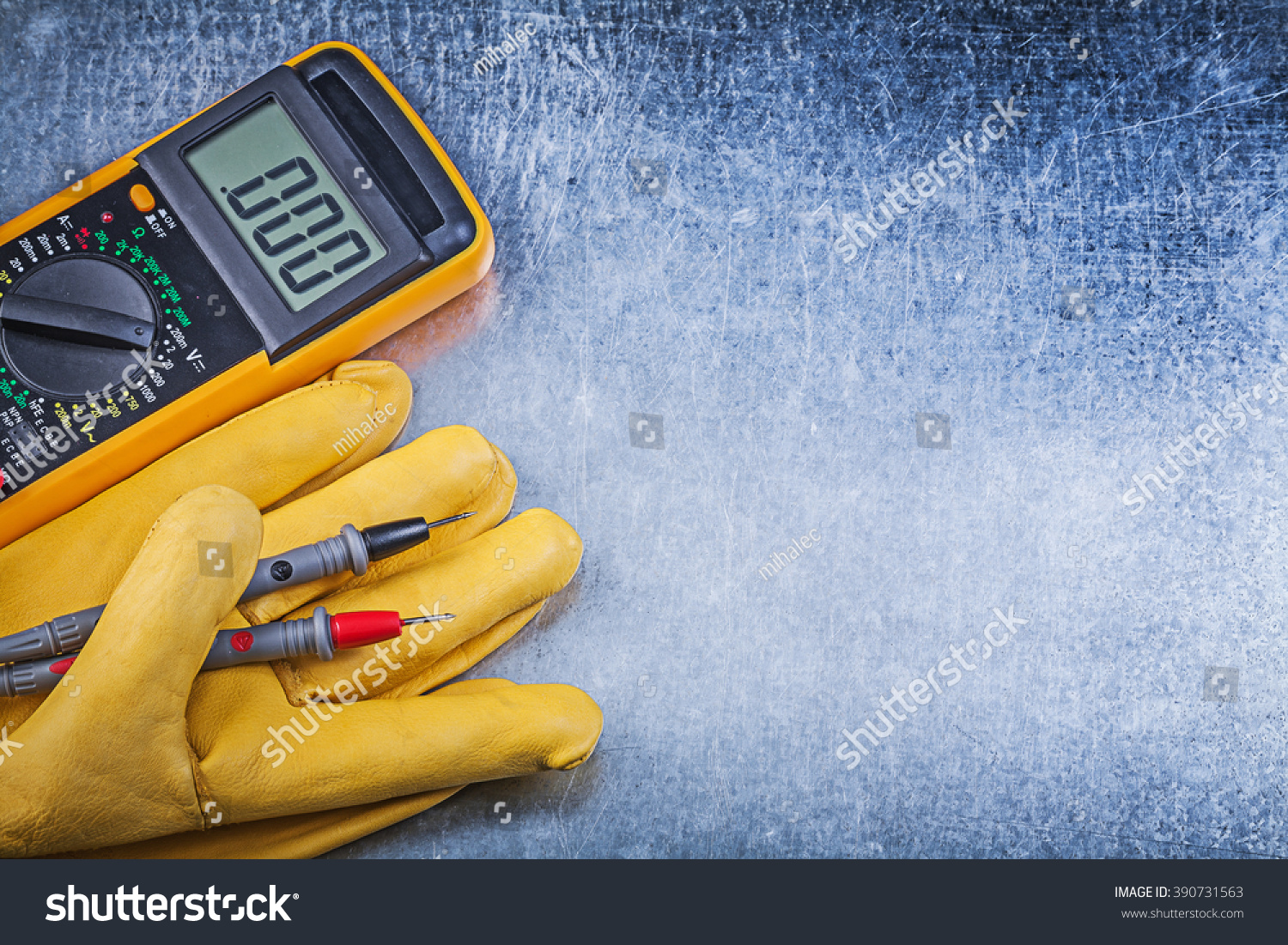 Digital electric tester safety gloves on metallic background electricity concept. #390731563