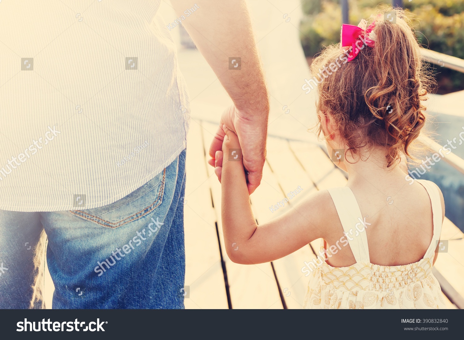 Toned portrait of Father and daughter holding hand in hand at sunset #390832840