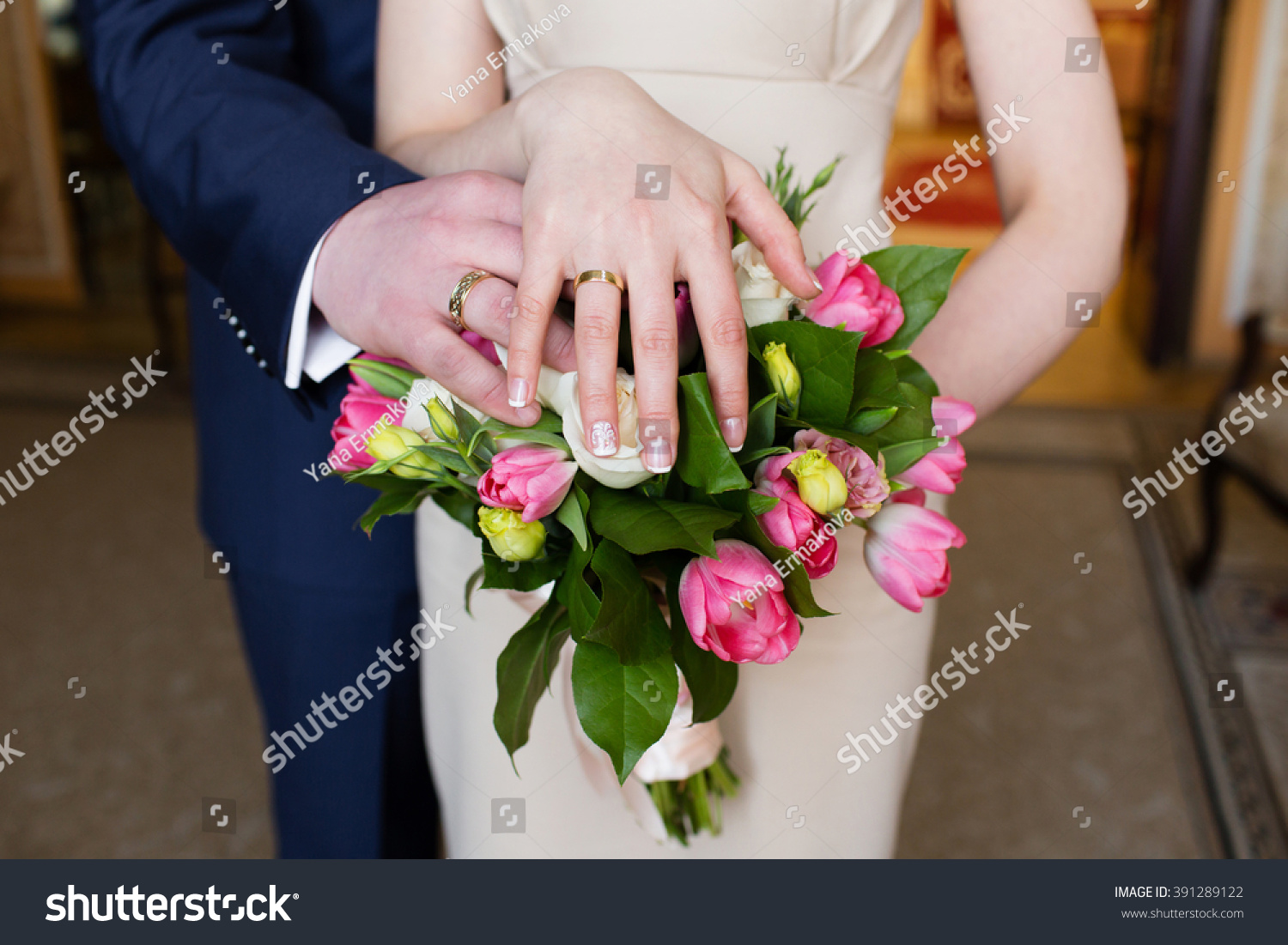 Hands of the groom and bride with rings and bridal bouquet #391289122