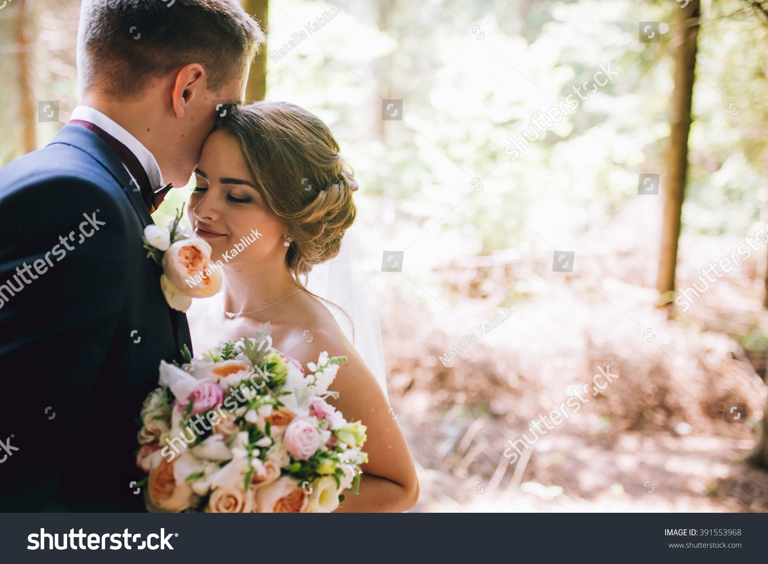 Bride and groom in a park kissing.couple newlyweds bride and groom at a wedding in nature green forest are kissing photo portrait.Wedding Couple #391553968