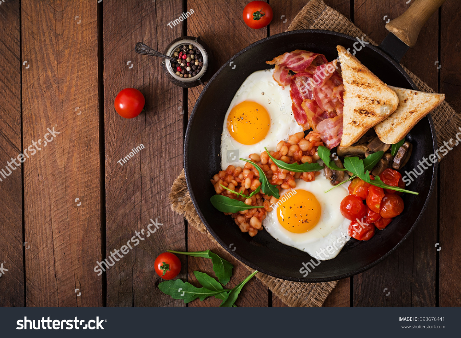 English breakfast - fried egg, beans, tomatoes, mushrooms, bacon and toast. Top view #393676441