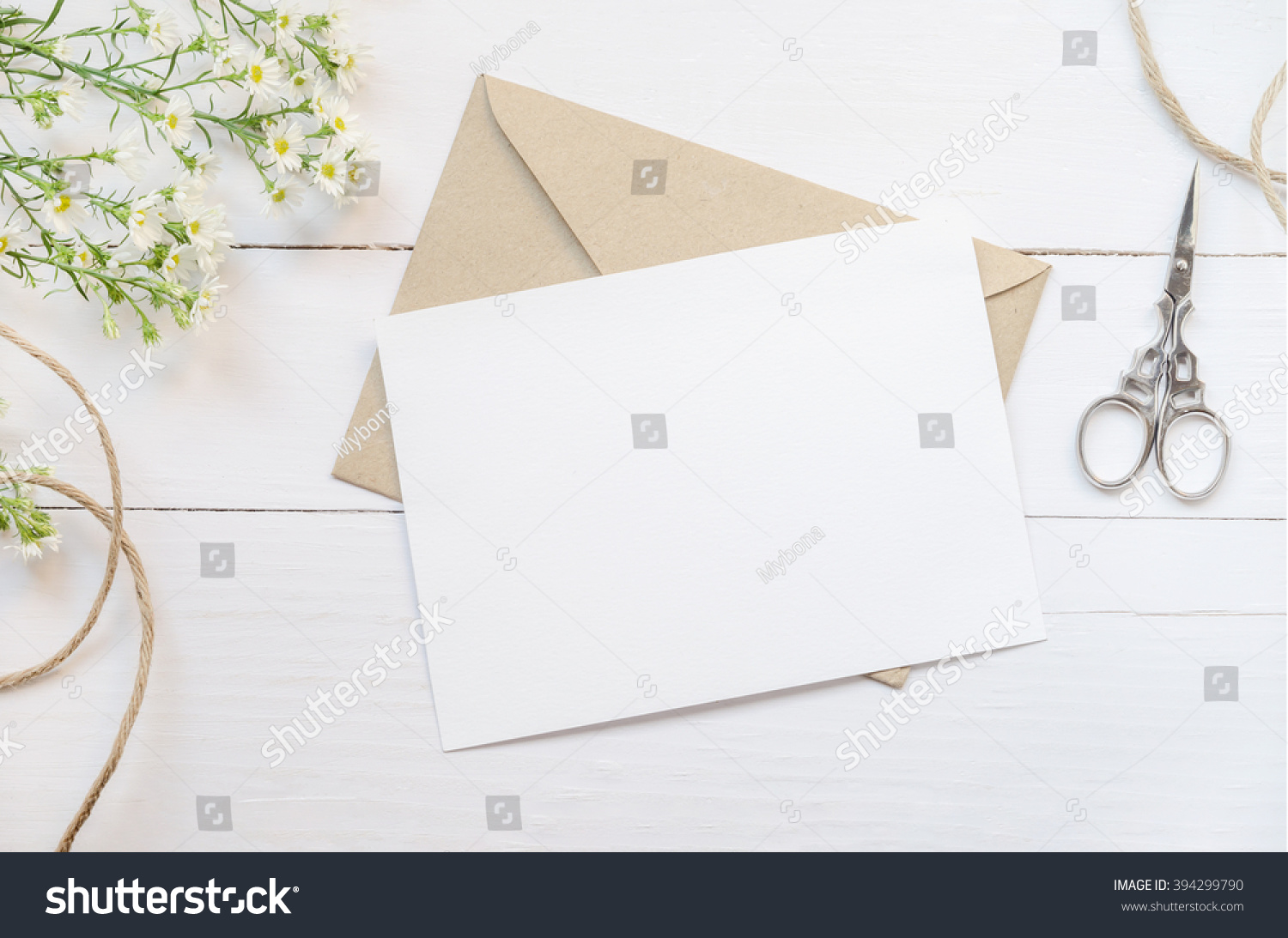 Blank white greeting card with brown envelop and daisy flowers on wooden table with vintage tone #394299790