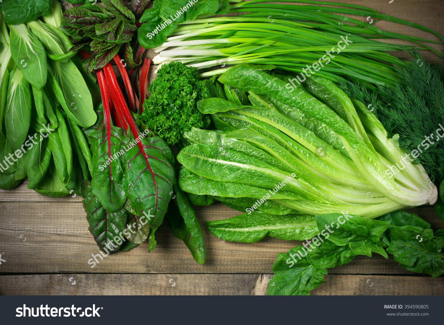 Spring vitamin set of various green leafy vegetables on rustic wooden table. Top view point. #394590805