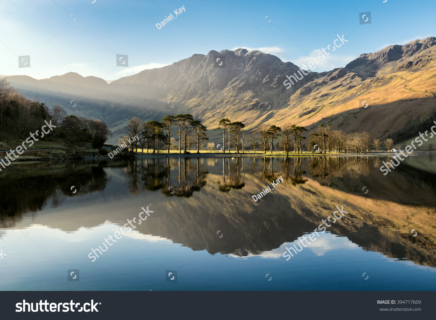 Beautiful morning sunlight shining on Buttermere in the Lake District with mirror like reflections.  #394717609