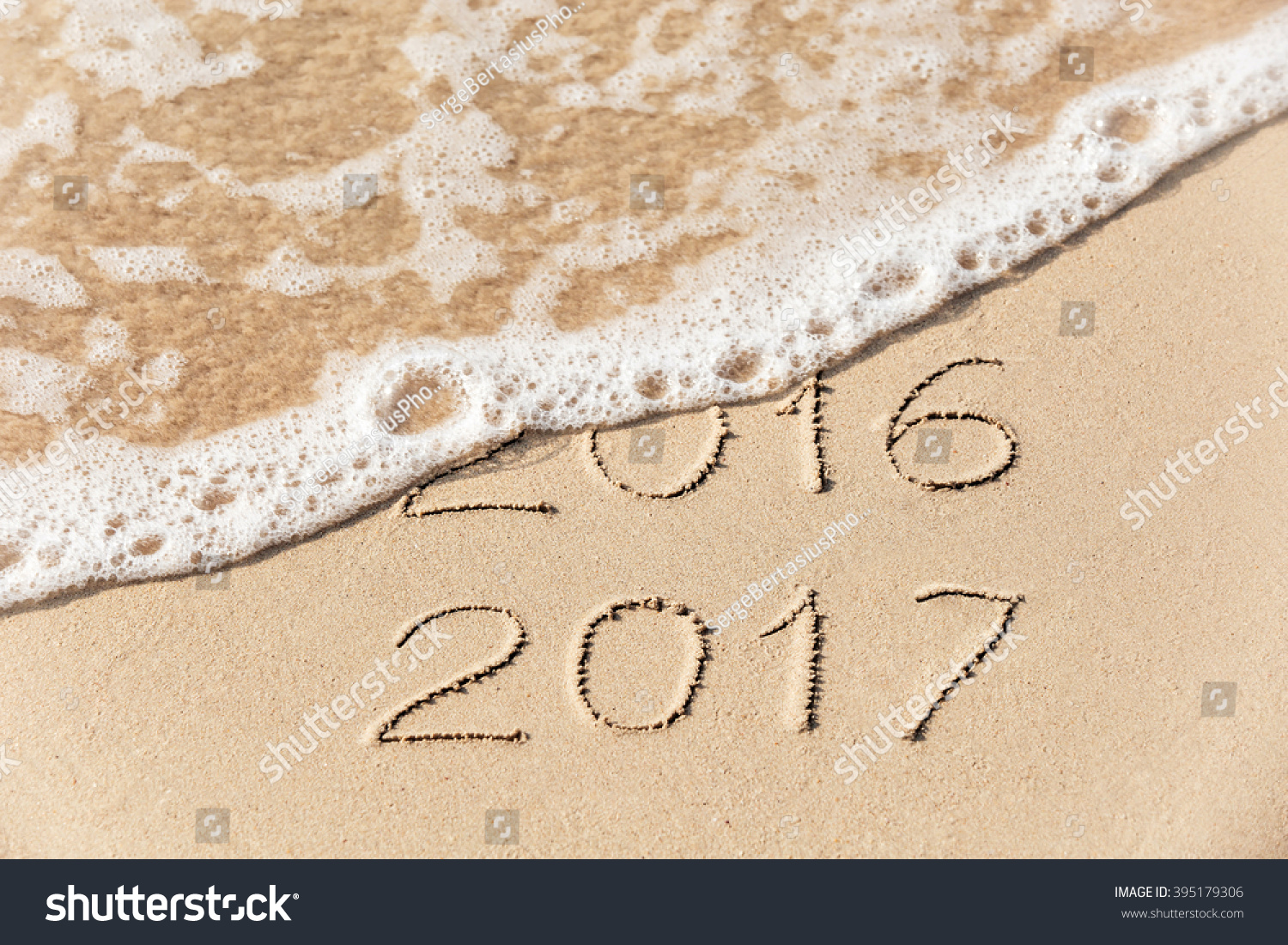 2016 2017  inscription written in the wet yellow beach sand being washed with sea water wave. Concept of celebrating the New Year at some exotic place #395179306