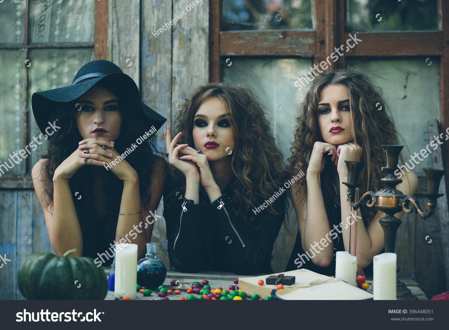 three witches are sitting at a table on the eve of Halloween #396448051