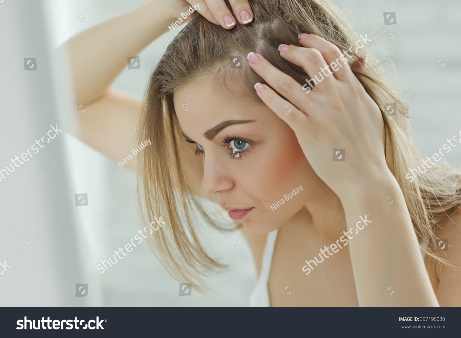 nervous girl looking in the mirror her scalp #397195030