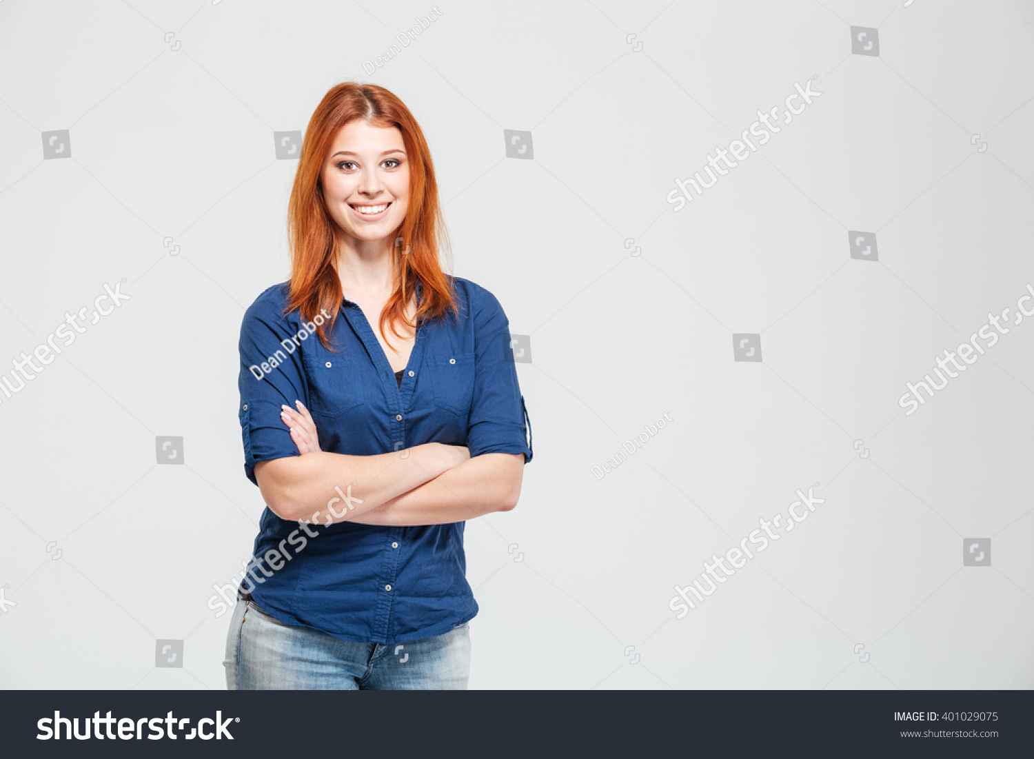 Cheerful pretty redhead young woman standing with hands folded over white background #401029075