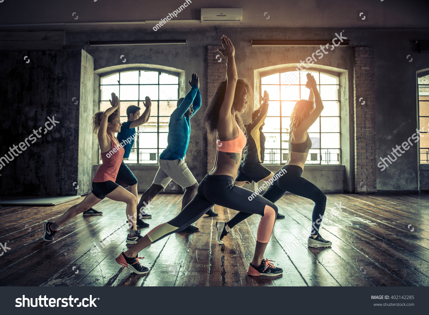 Group of sportive people in a gym training - Multiracial group of athletes stretching before starting a workout session #402142285