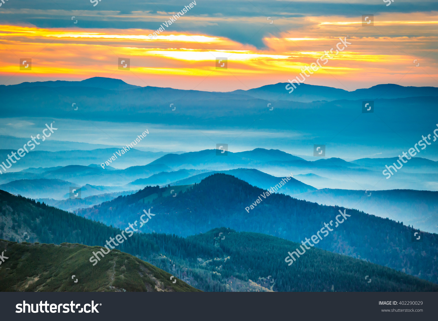 Sunset in the mountains. Dramatic colorful clouds over blue hills #402290029