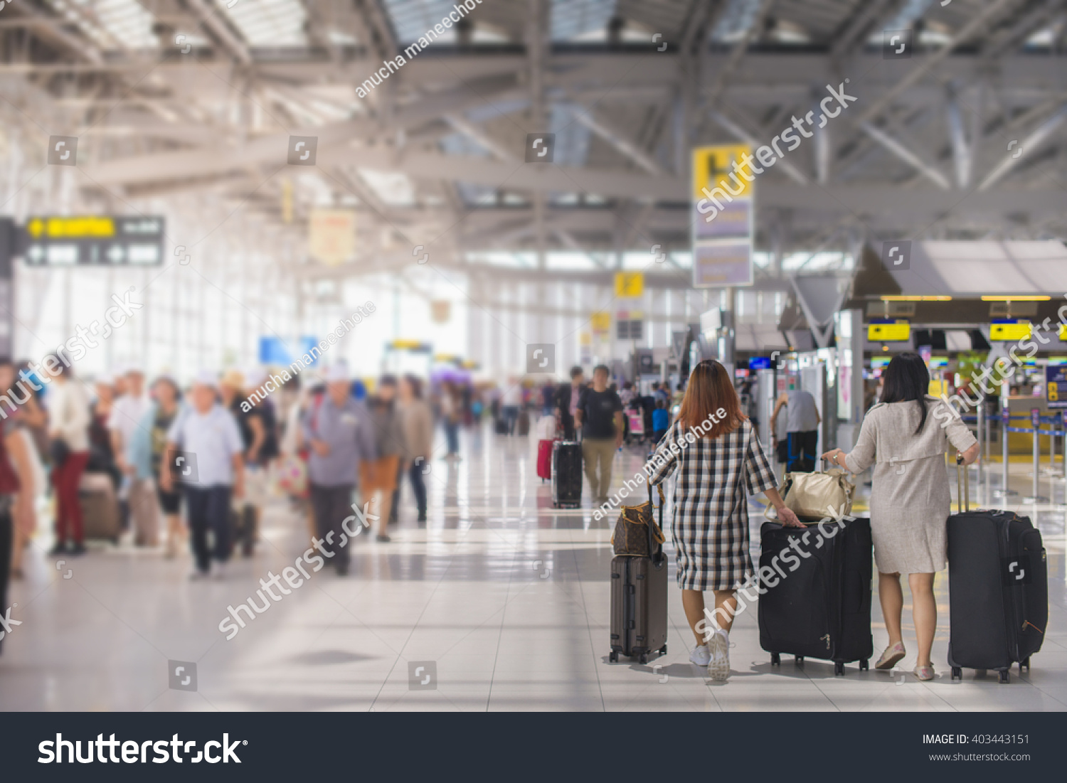 woman carries luggage at the airport terminal. #403443151