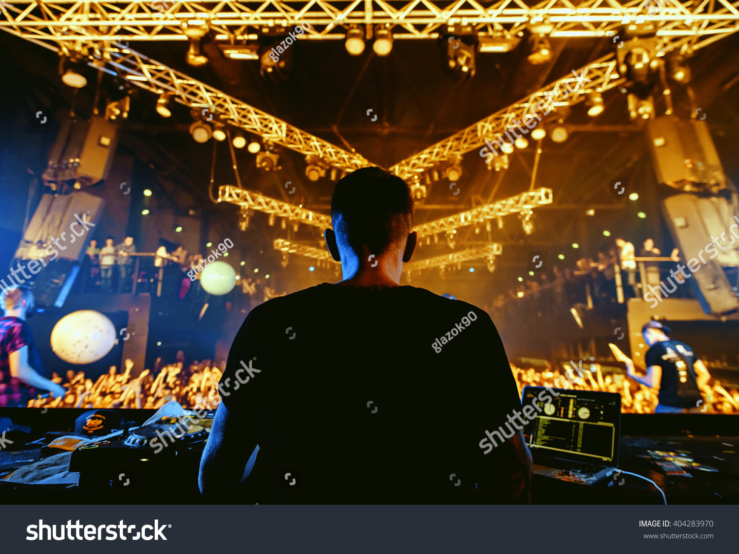 DJ hands up at night club party under yellow lasers with crowd of people #404283970