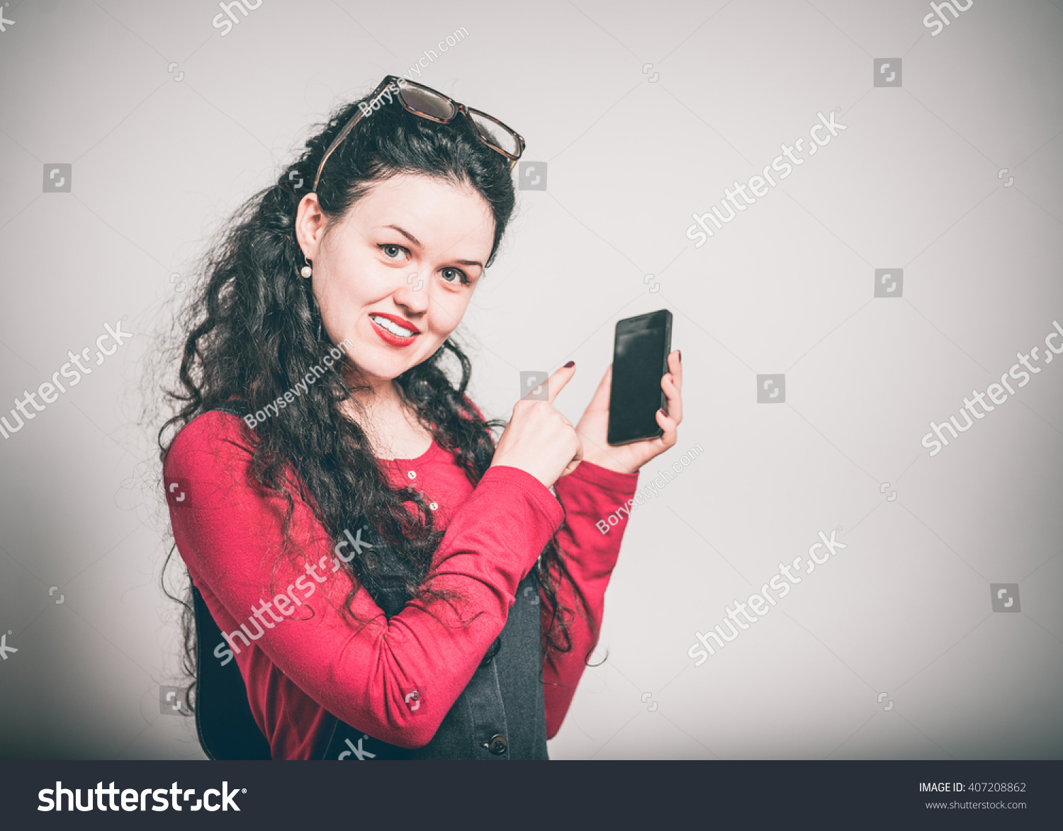 young woman enjoying a touchscreen phone, dressed in a overalls, close-up isolated on a gray background #407208862