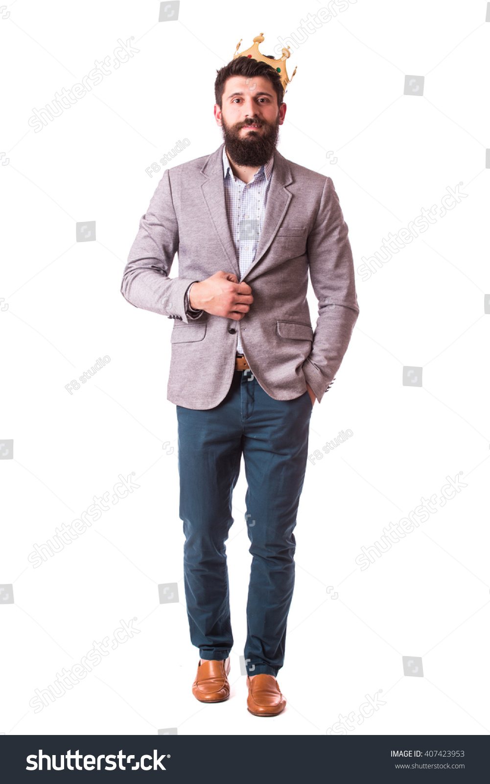 Handsome young cheerful man in suit with crown while standing against white background #407423953