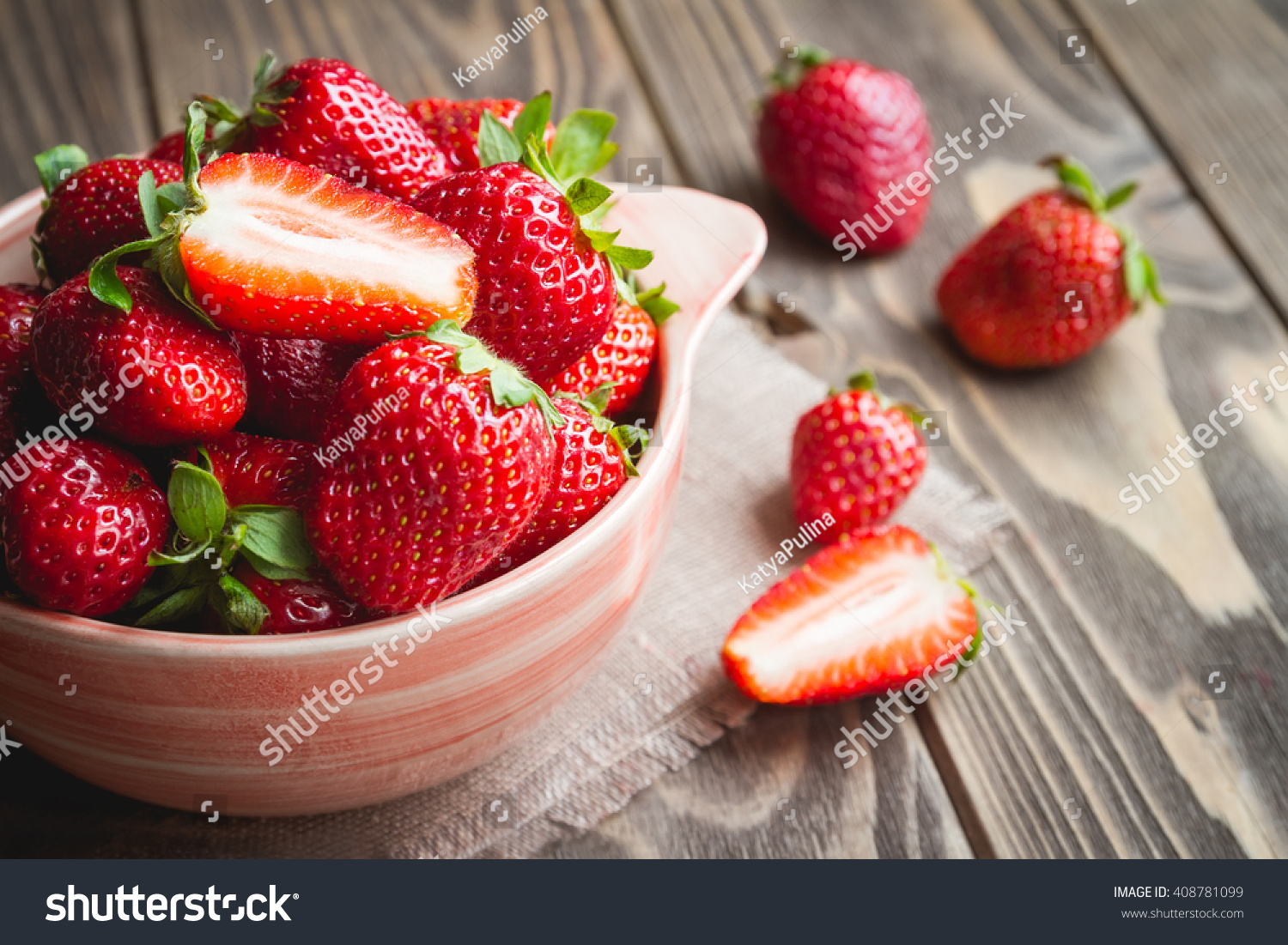 Fresh strawberries in a bowl on wooden table with low key scene. #408781099