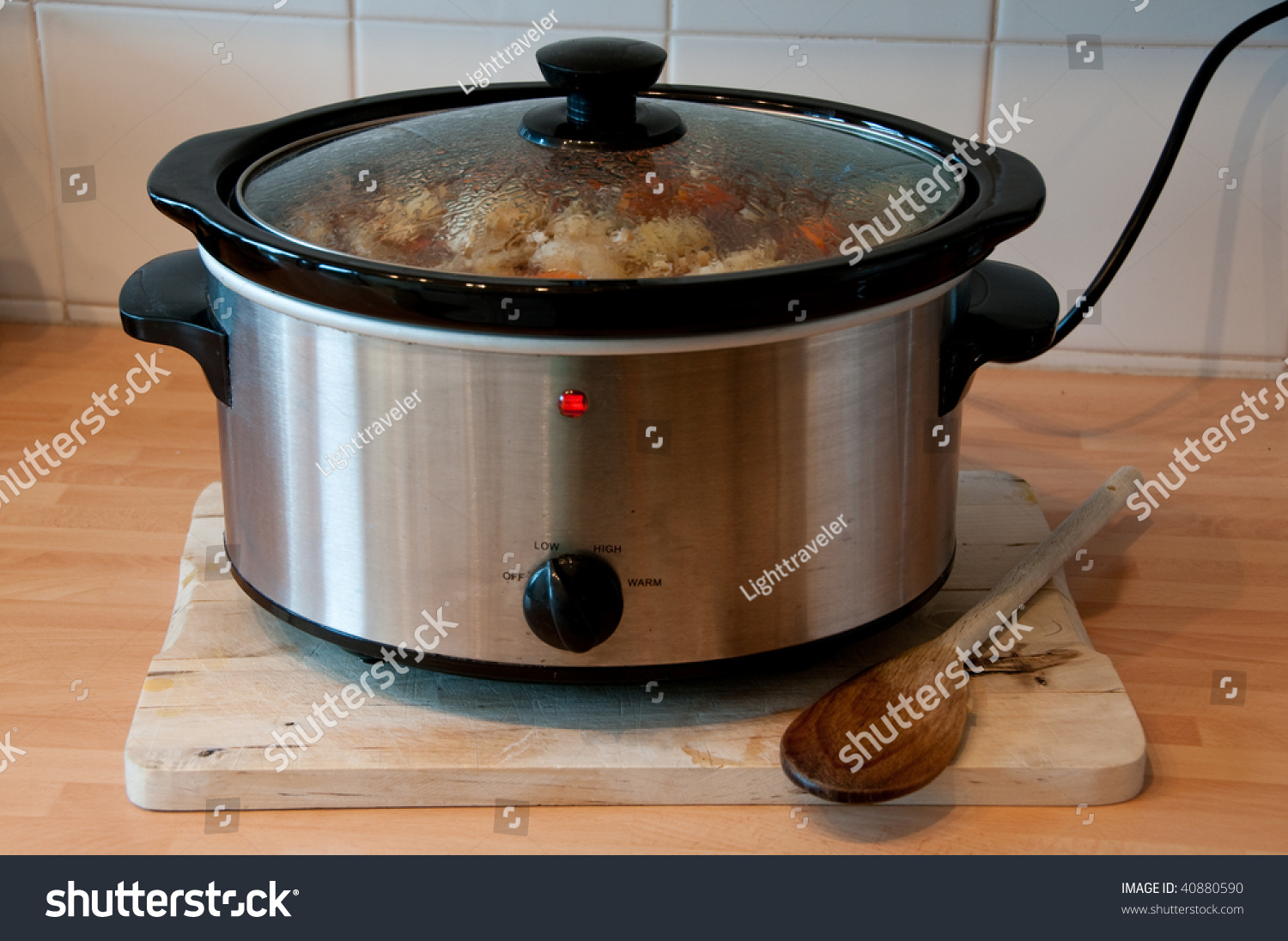 Slow cooker with wooden spoon on chopping board cheep winter cooking #40880590
