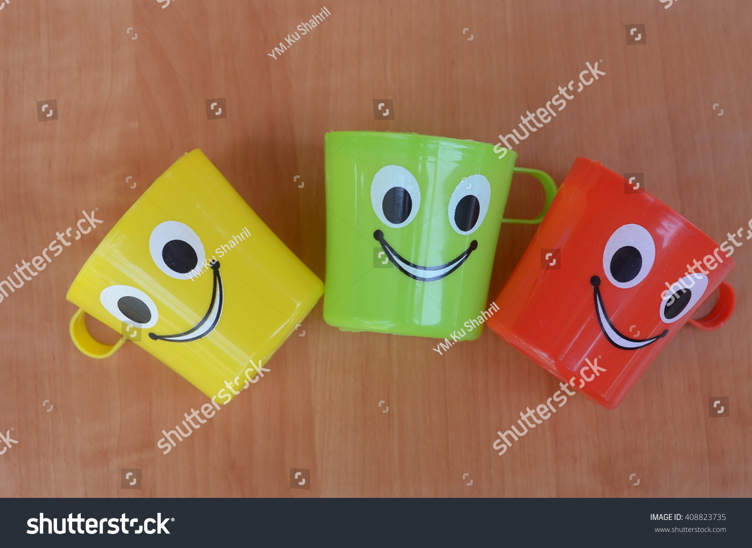  multi colored plastic kid mugs with smile symbol- Isolated wood texture  #408823735