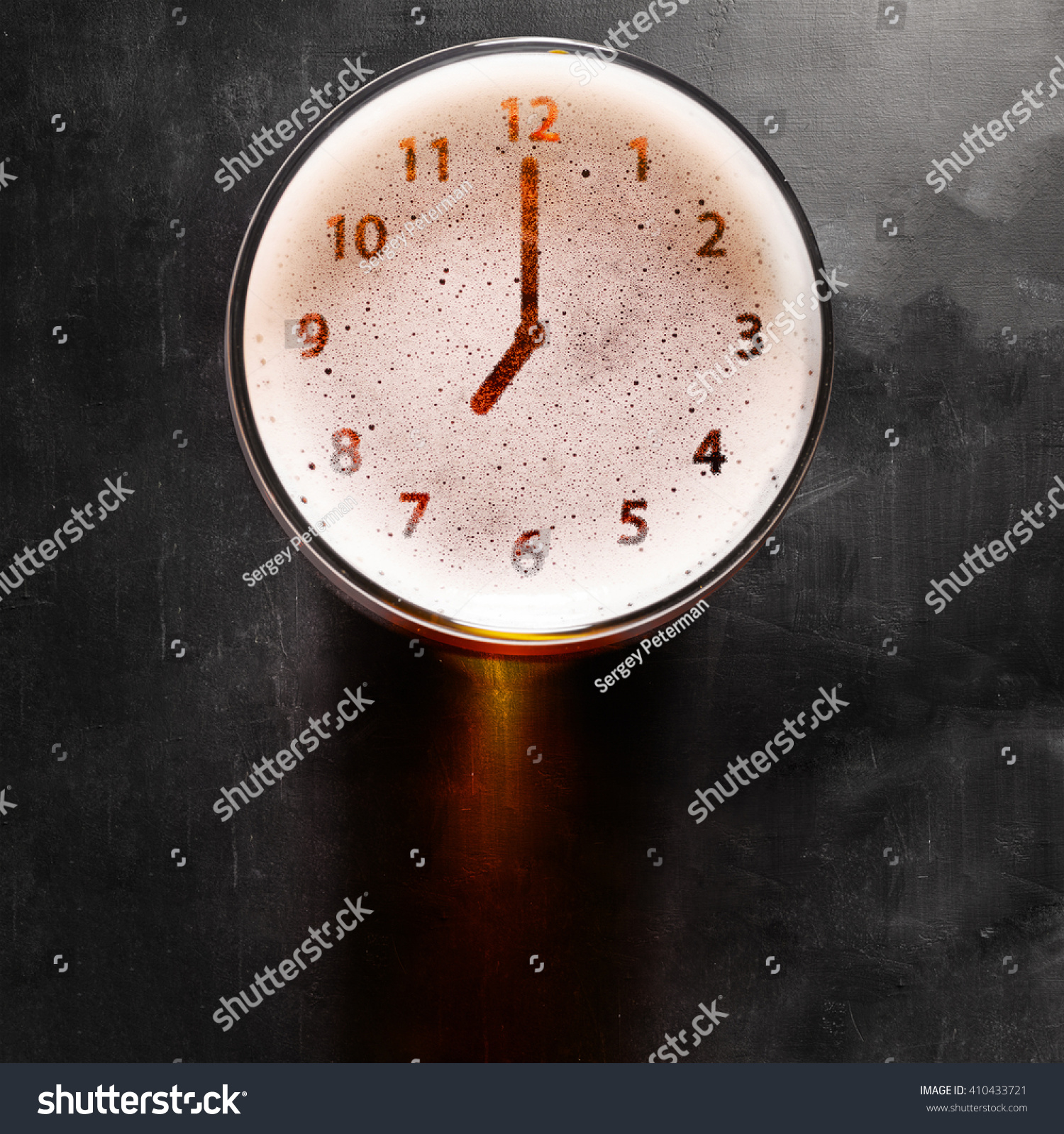 clock symbol on foam in beer glass on black table, view from above #410433721
