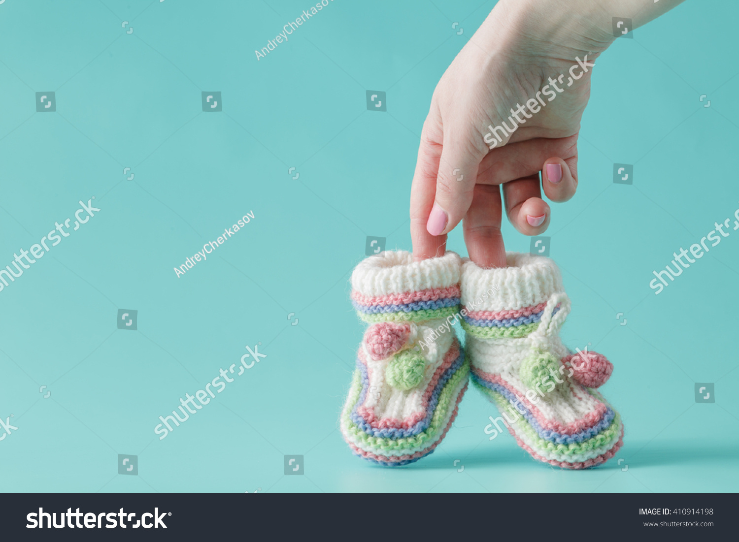 female hand holds small baby shoes #410914198