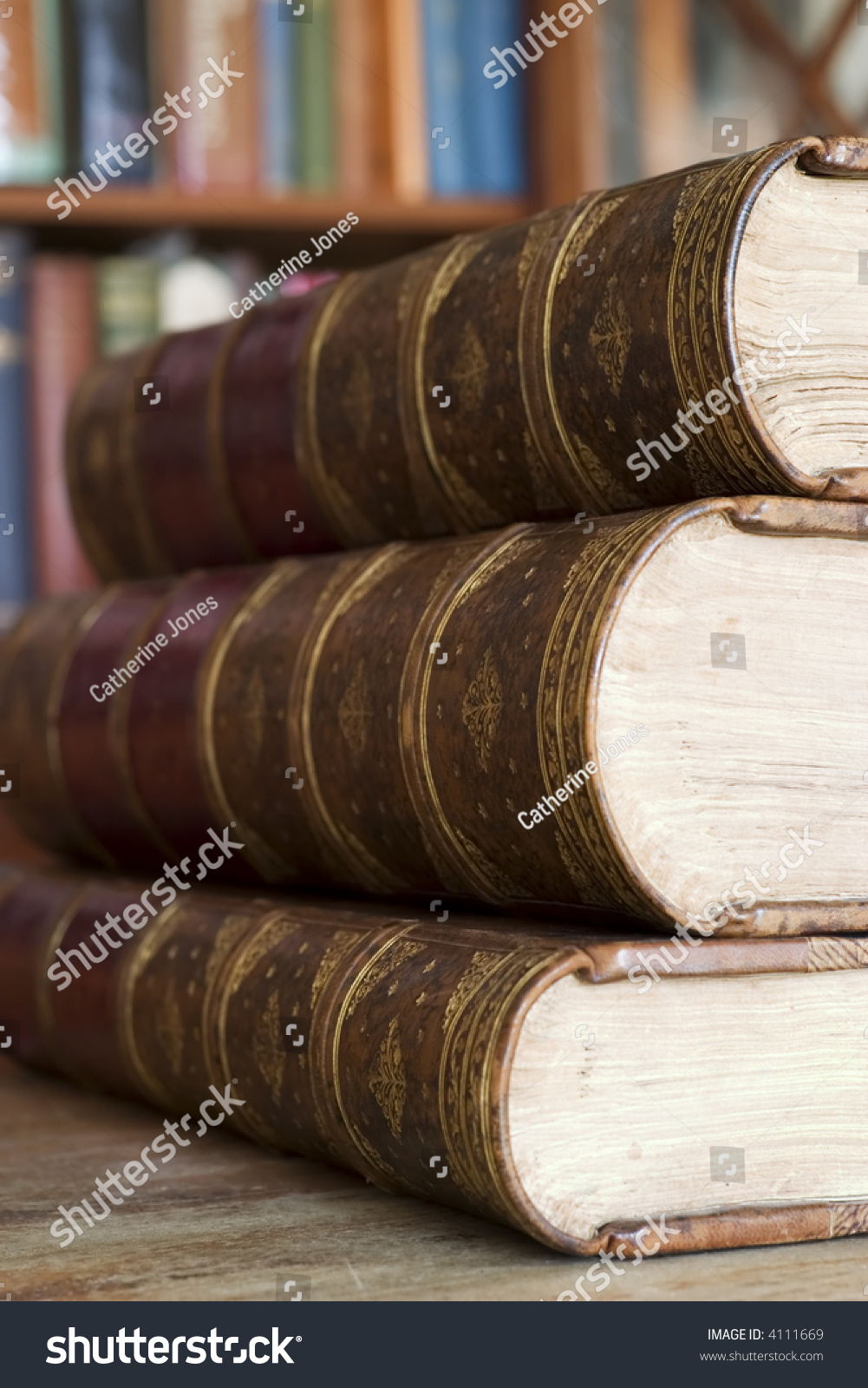 Three old books in front of library shelves #4111669