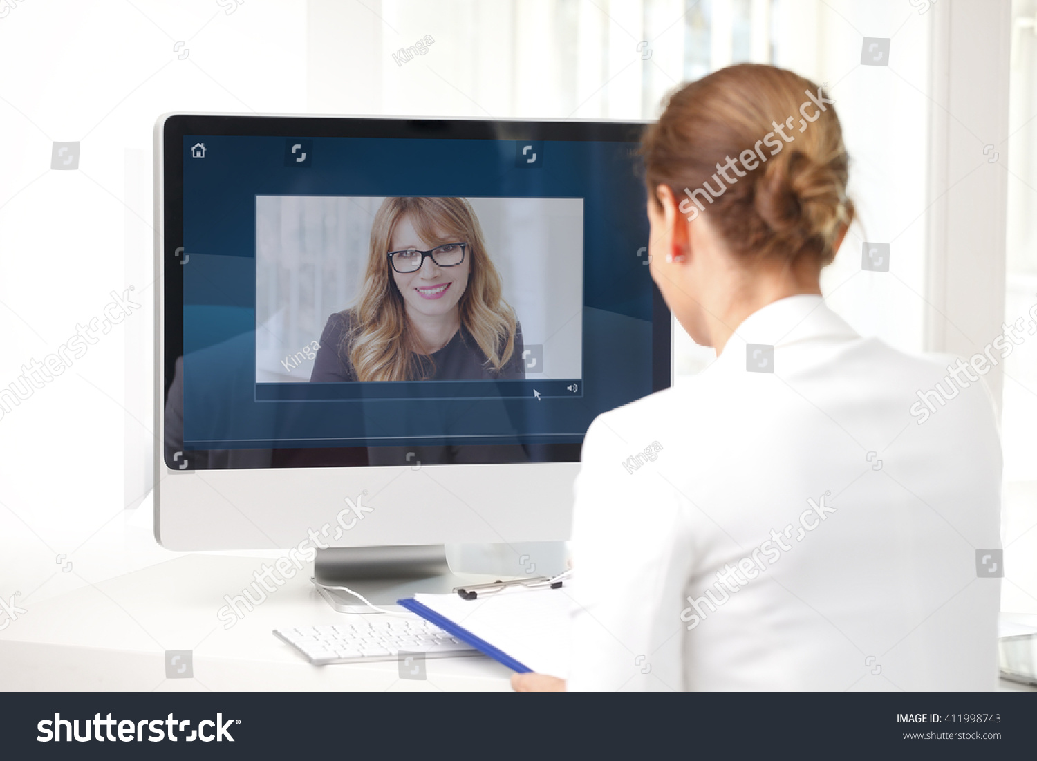 Rear view shot of middle age businesswoman sitting at her workplace and having video chat with executive professional woman.  #411998743