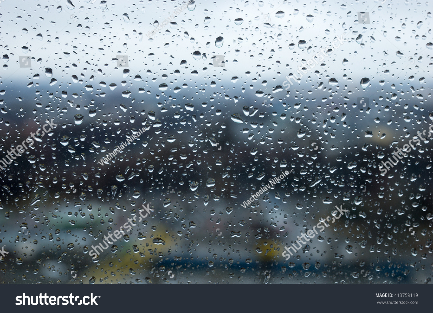 Raindrops or water droplets beaded on the surface of a glass window pane with blurred background #413759119