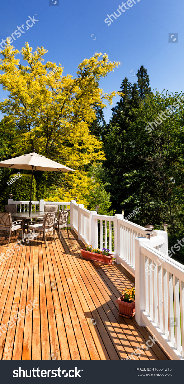 Residential outdoor cedar deck with furniture and umbrella during nice bright day. Vertical layout.  #416551216