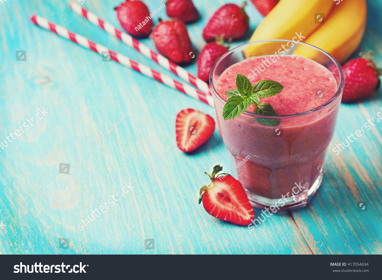 smoothie with banana and strawberry in the glass, fresh strawberries and bananas on the  wooden background (toning) #417054694