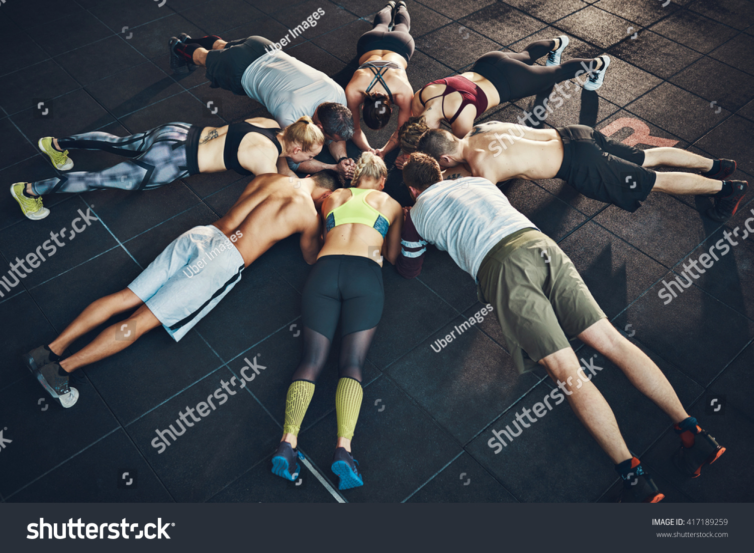 Fit young people focused on planking in a circle in a gym #417189259