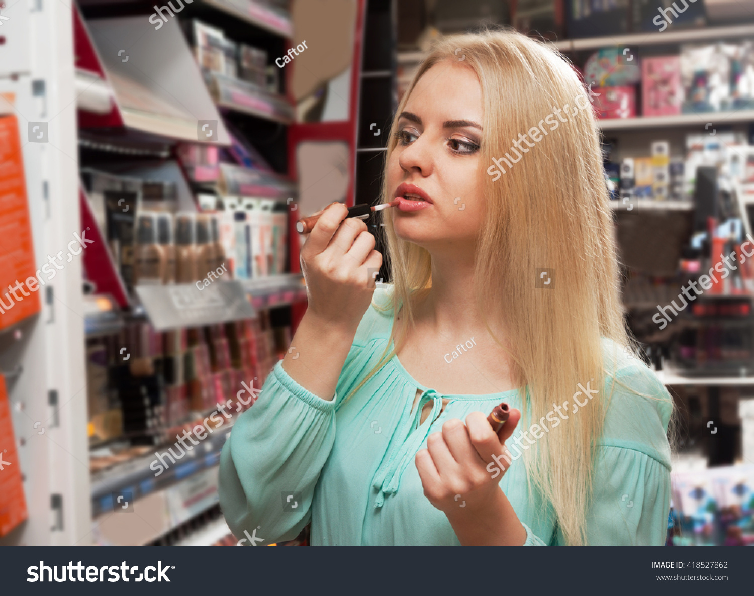 Portrait of smiling young blondie selecting lip gloss in store #418527862
