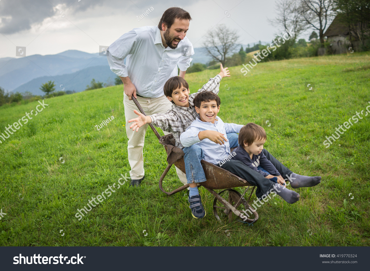 Father playing with sons using trolley on meadow #419770324