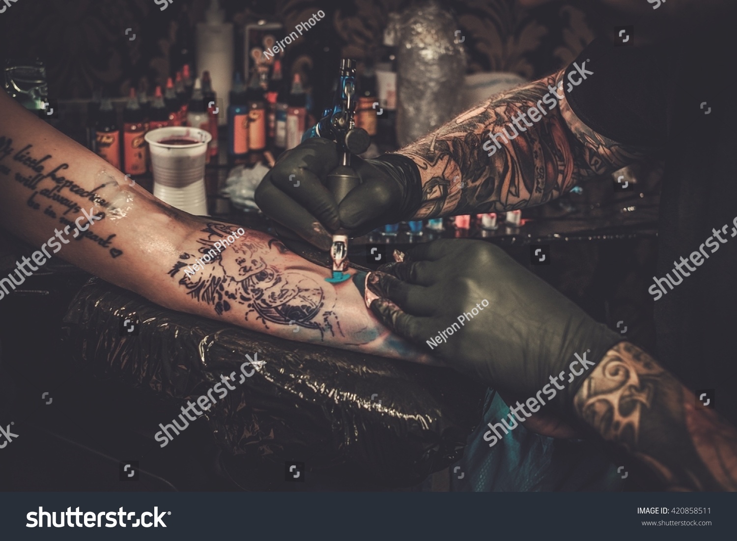 Professional tattoo artist makes a tattoo on a young girl's hand.  #420858511