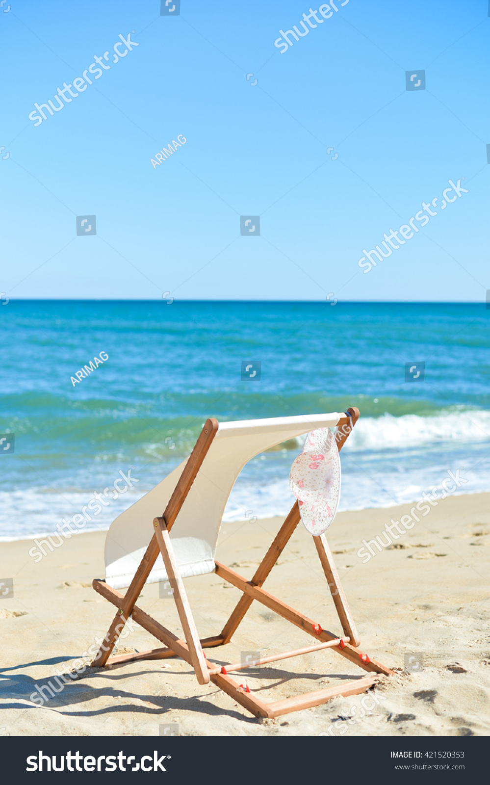 Female hat and deckchair on the beach vacation, sunny outdoors background #421520353